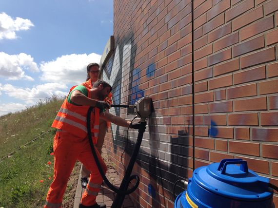 removing graffiti professional with cleaning equipment